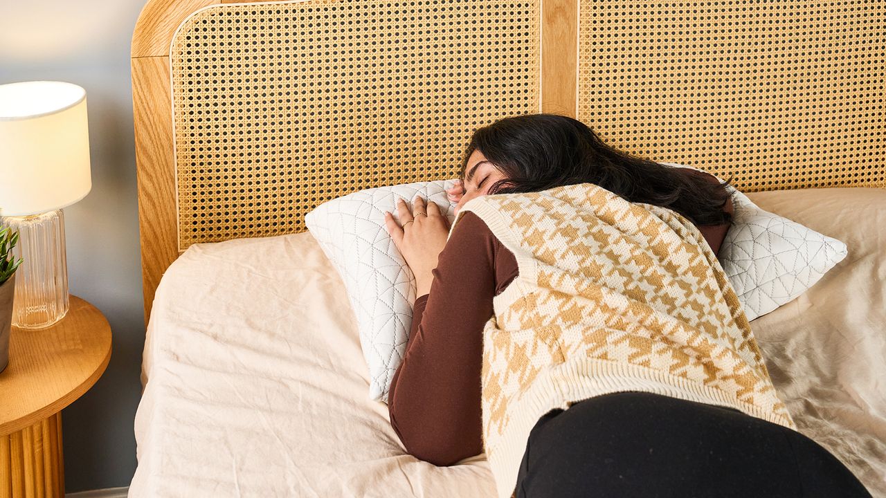 Woman sleeping on a white pillow placed on a bed with a rattan headboard