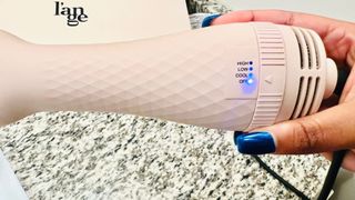 A person holding a pink L'ange dryer brush showing the three heat settings for the L'ange blow dryer brush review.