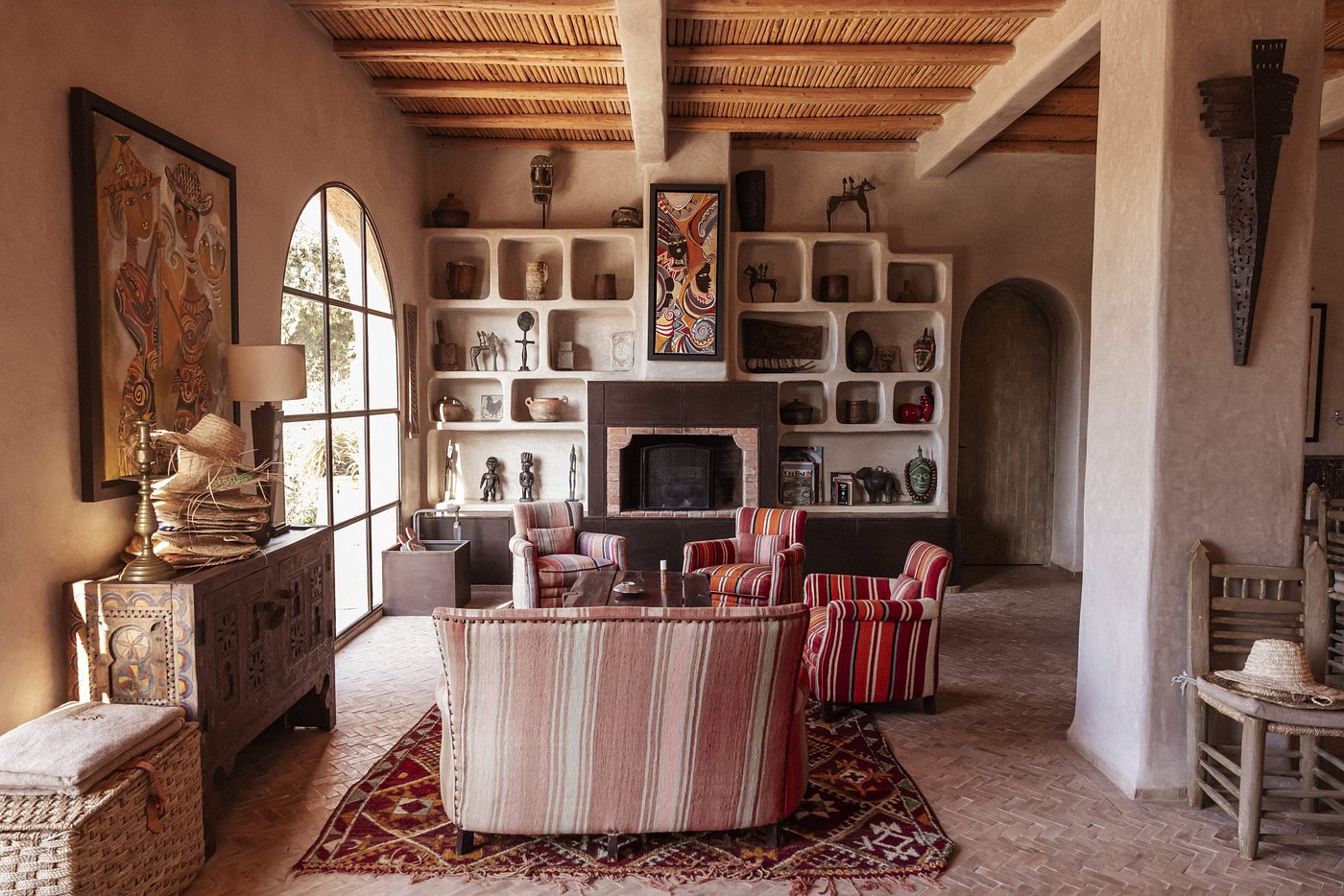 The cozy, layered interiors of a Moroccan residence sculpted from terracotta surfaces, Berber rugs, colourful artworks, and built-in shelves.