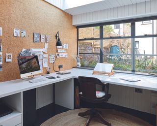Artists studio in garden room, with a corner desk, Mac computer, black desk chair and a view out to the garden