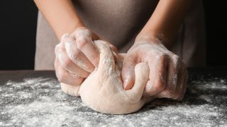 Someone kneading bread dough on a surface
