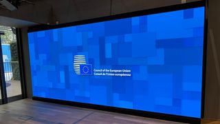 A large, curved bright blue LED video wall showing the European Union logo.