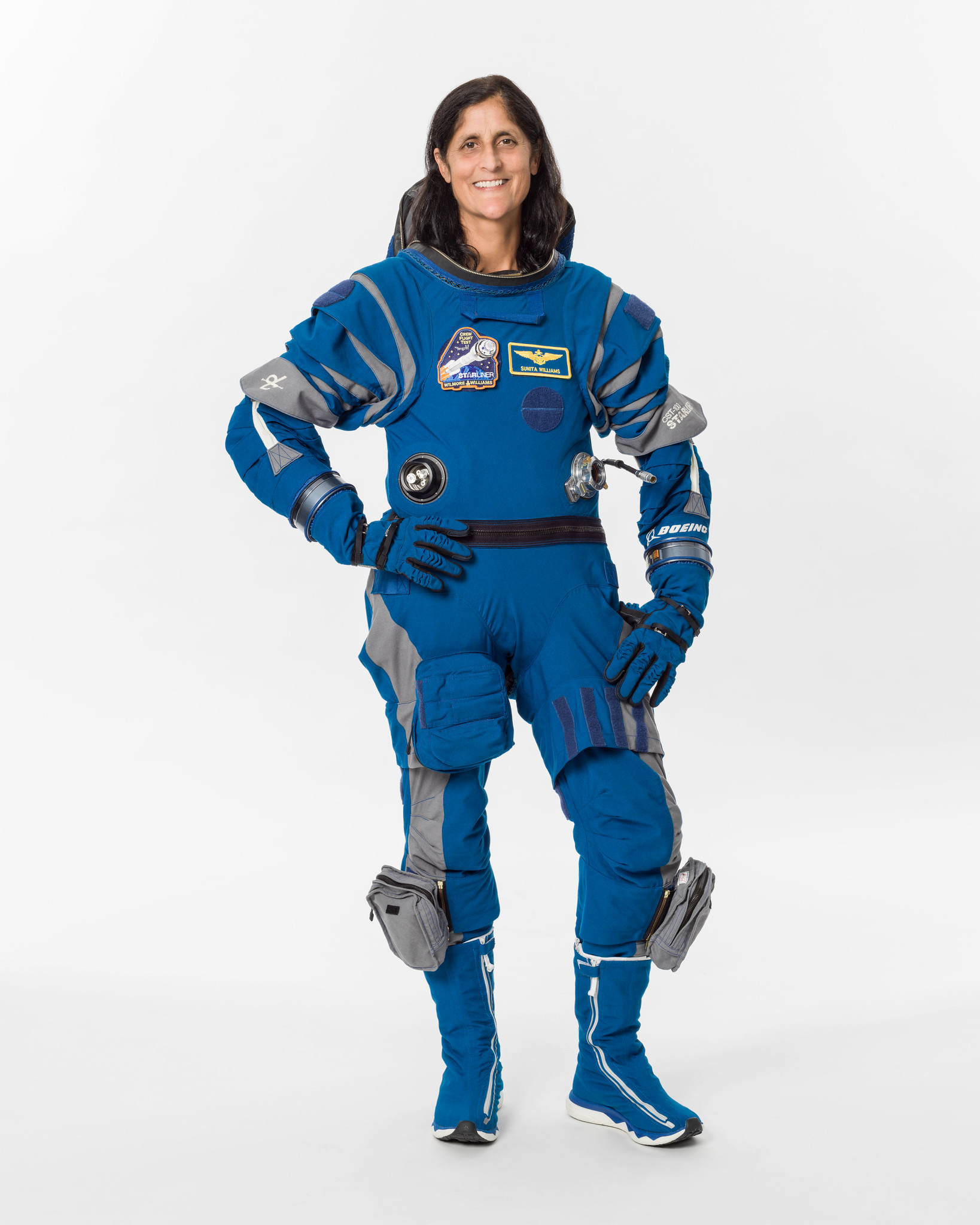 an astronaut poses for a portrait in a blue flight suit