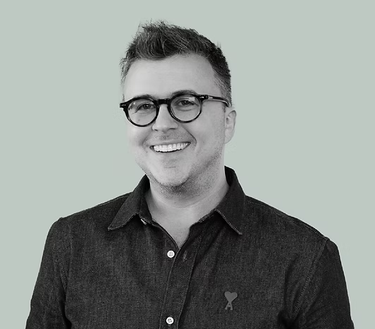 a black and white headshot of a white man with glasses