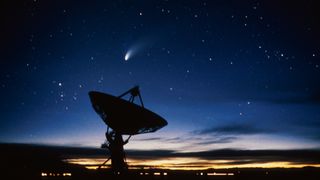 a bright comet in the sky over a large antenna dish