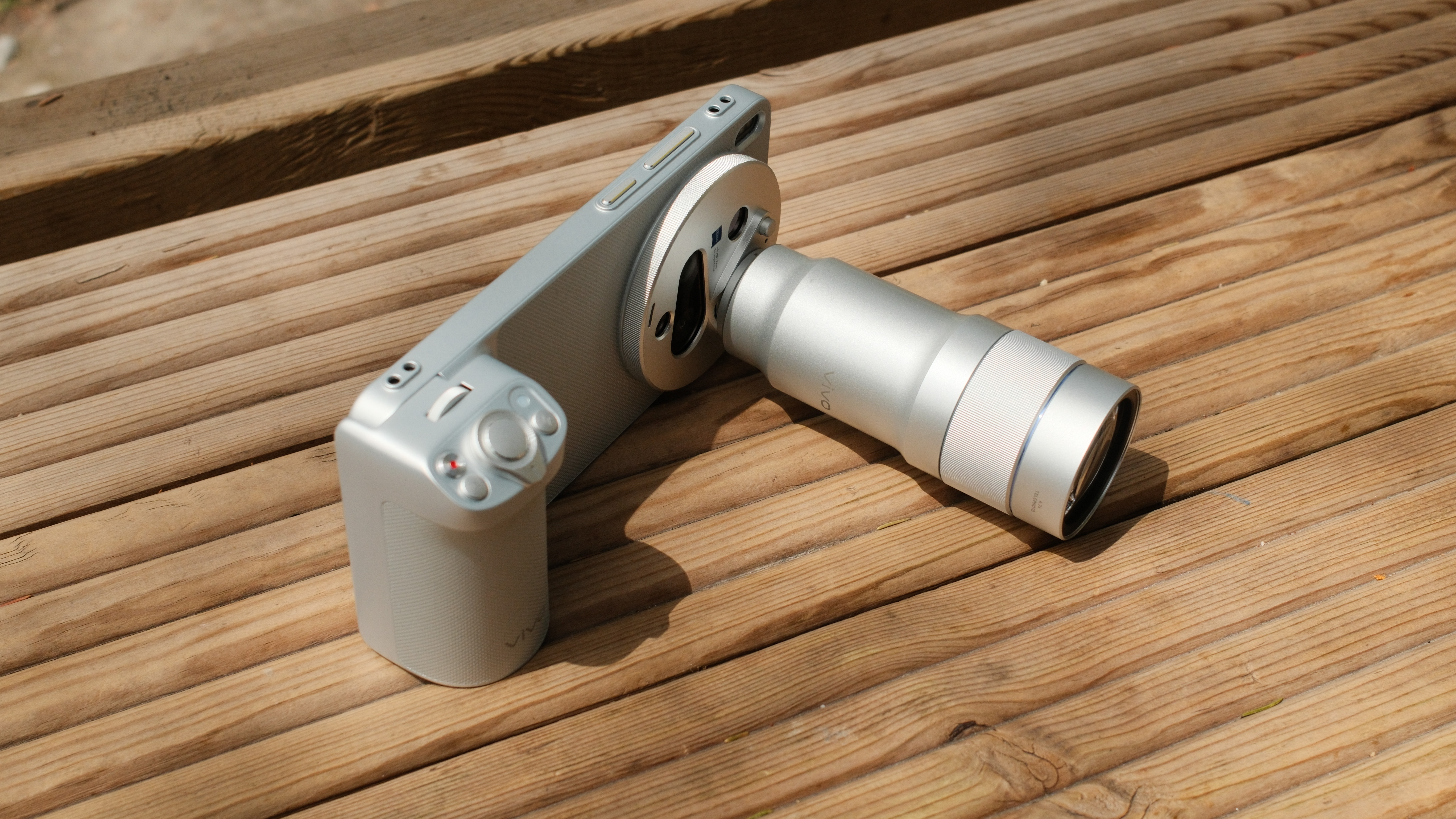 Vivo X300 Ultra accessory grip and telephoto lens mounted on a wooden bench