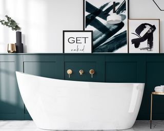 Freestanding white tub with dark green wall paneling and framed art by Bathroom Mountain