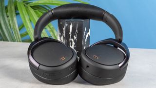 A pair of black Edifier WH950NB over-ear headphones photographed against a blue background