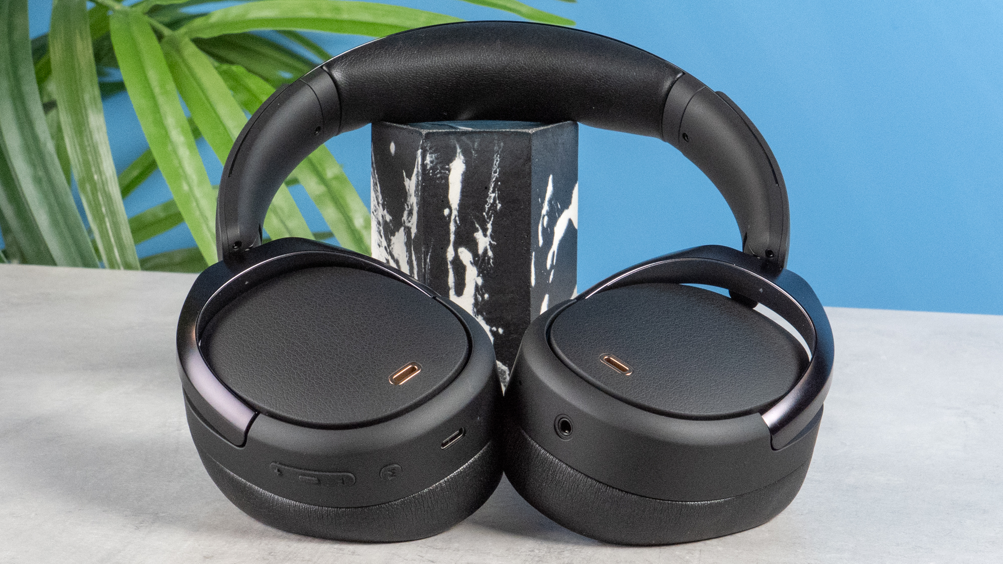 A pair of black Edifier WH950NB over-ear headphones photographed against a blue background