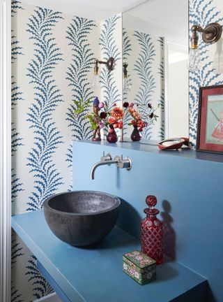 Small powder room with blue painted vanity and patterned blue and white coastal wallpaper