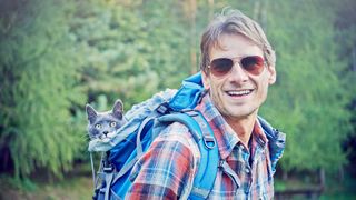 Man hiking with cats in backpack