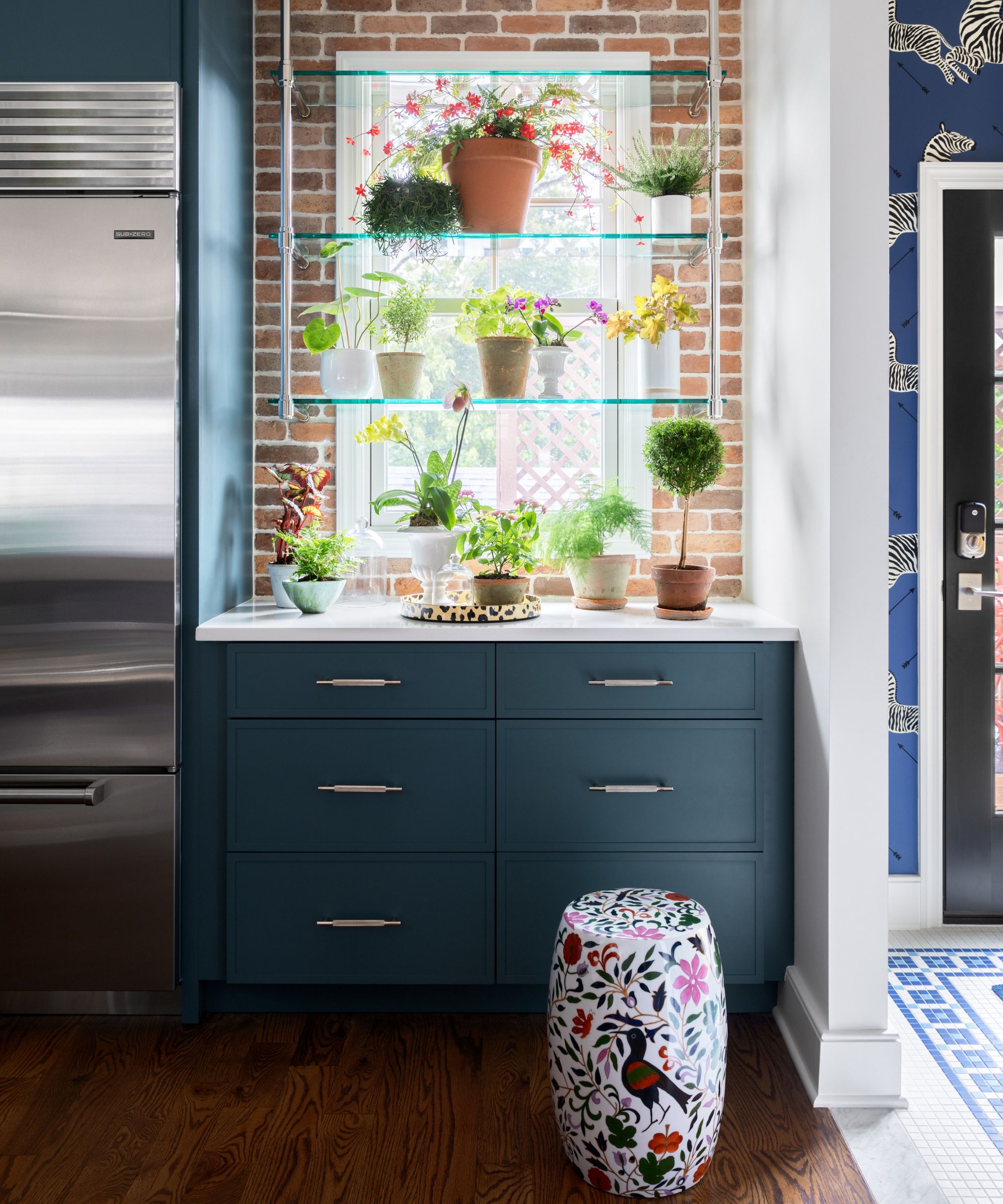 Kitchen window with shelving in front and blue cabinetry beneath