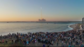 A crowd of people on a beach watches the second-ever test flight of SpaceX's giant Starship vehicle on Nov. 18, 2023.