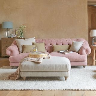 A light pink sofa with a cream footstool