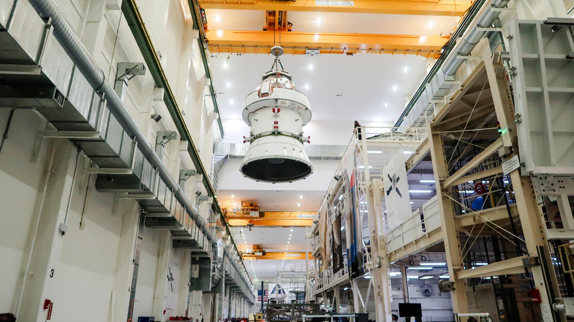 a cone-shaped spacecraft in the rafters being hoisted between the walls