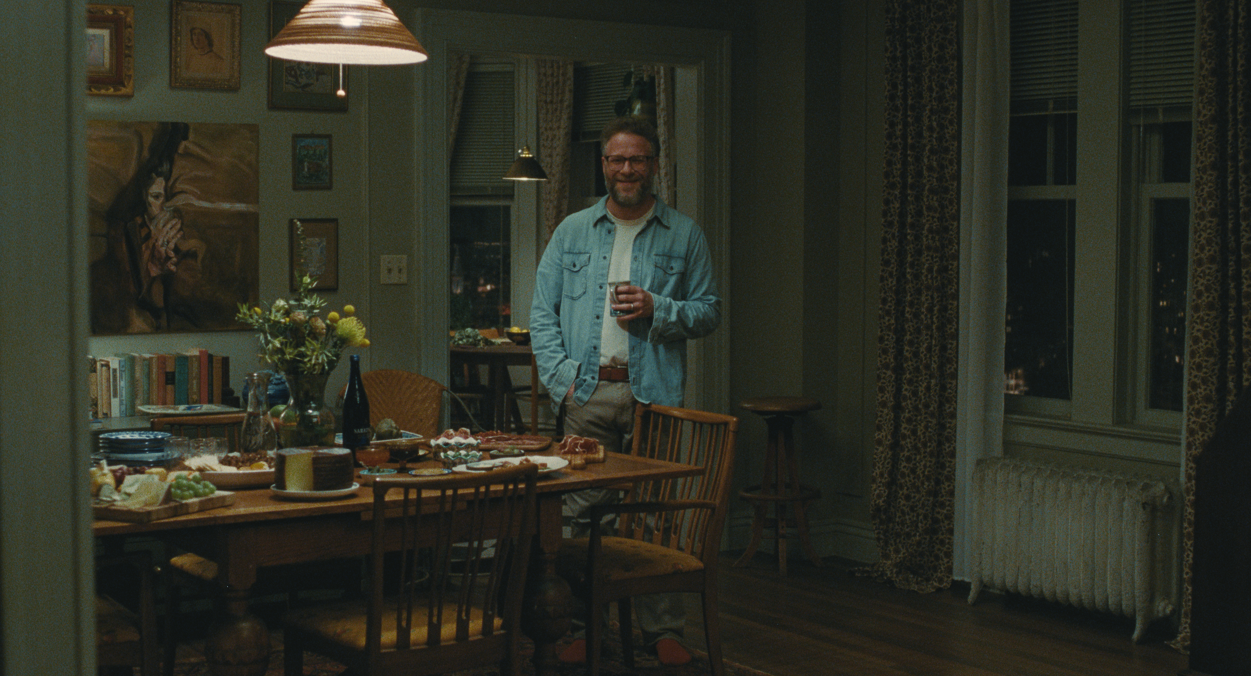 seth rogen as joe standing in front of a dinner table with charcuterie in a still from the invite