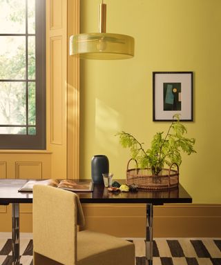 room with yellow walls, dark yellow woodwork, desk with plant in front of window