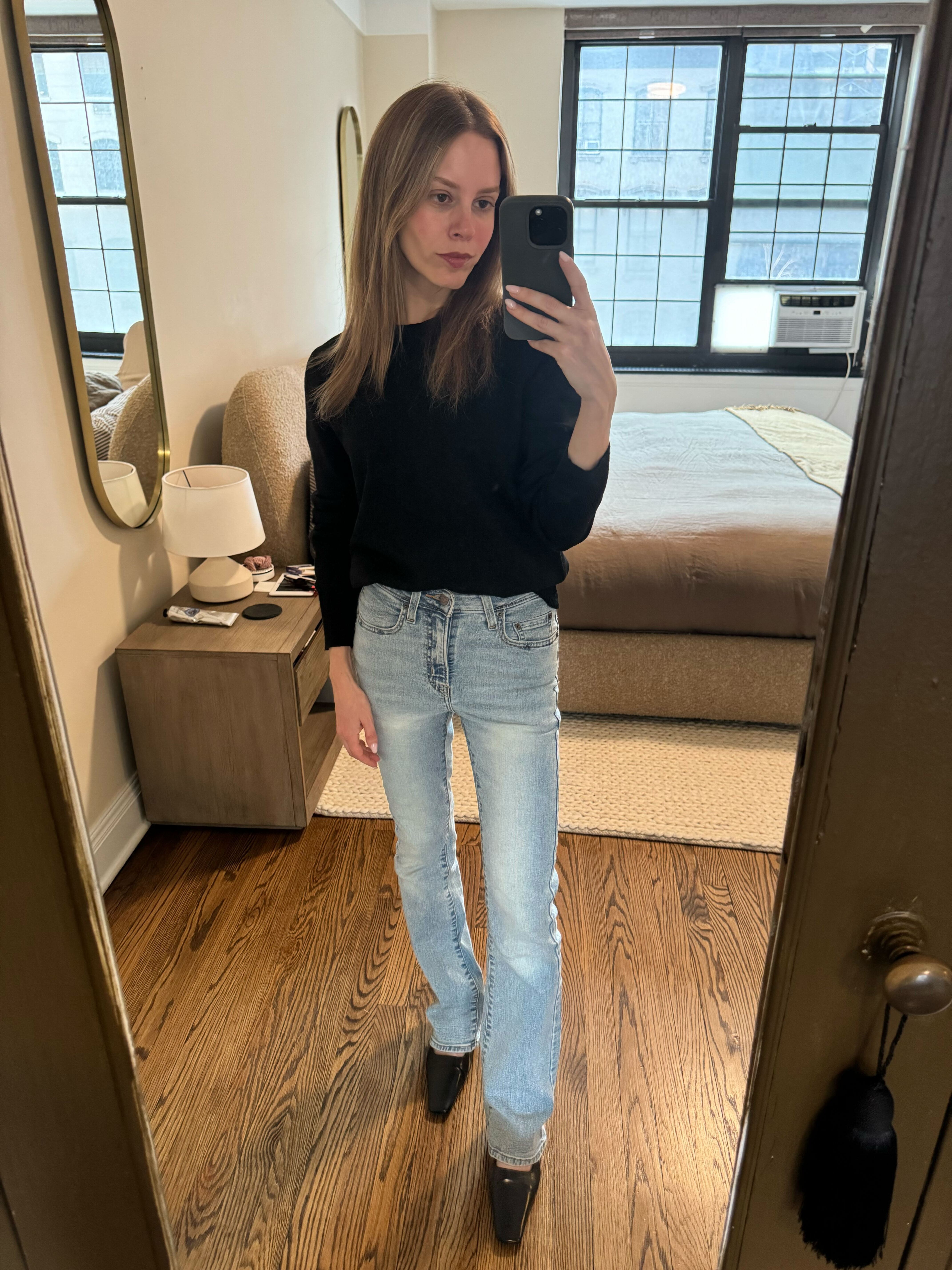 Nikki wears a black sweater, Levi's jeans, and pumps.
