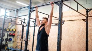 Man hanging off a pull-up bar in a gym