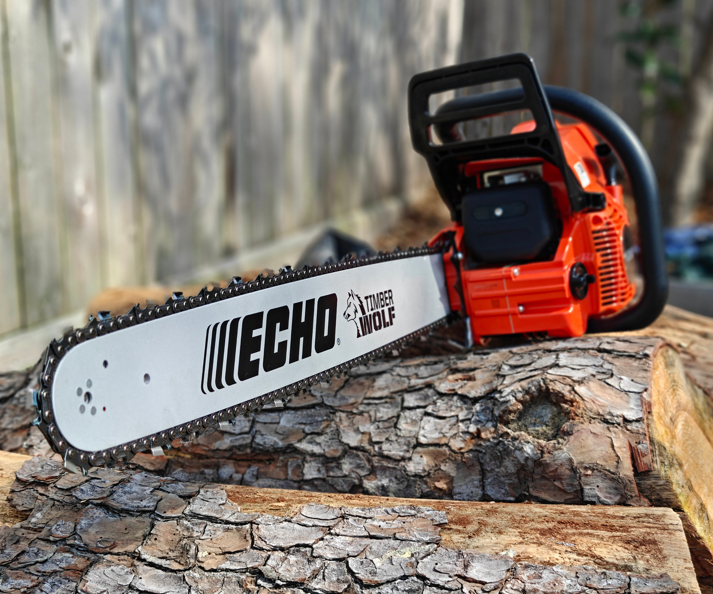 Stylized photo of the Echo CS-590 chainsaw sitting on a pile of logs with a fence in the background