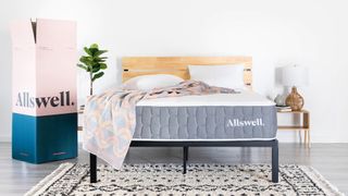 Best firm mattress: the Allswell Brick mattress photographed on a black metal bed frame and stood next to the pink and blue box its shipped in