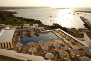 Neat rows of parasols and sun beds line a modernist outdoor pool