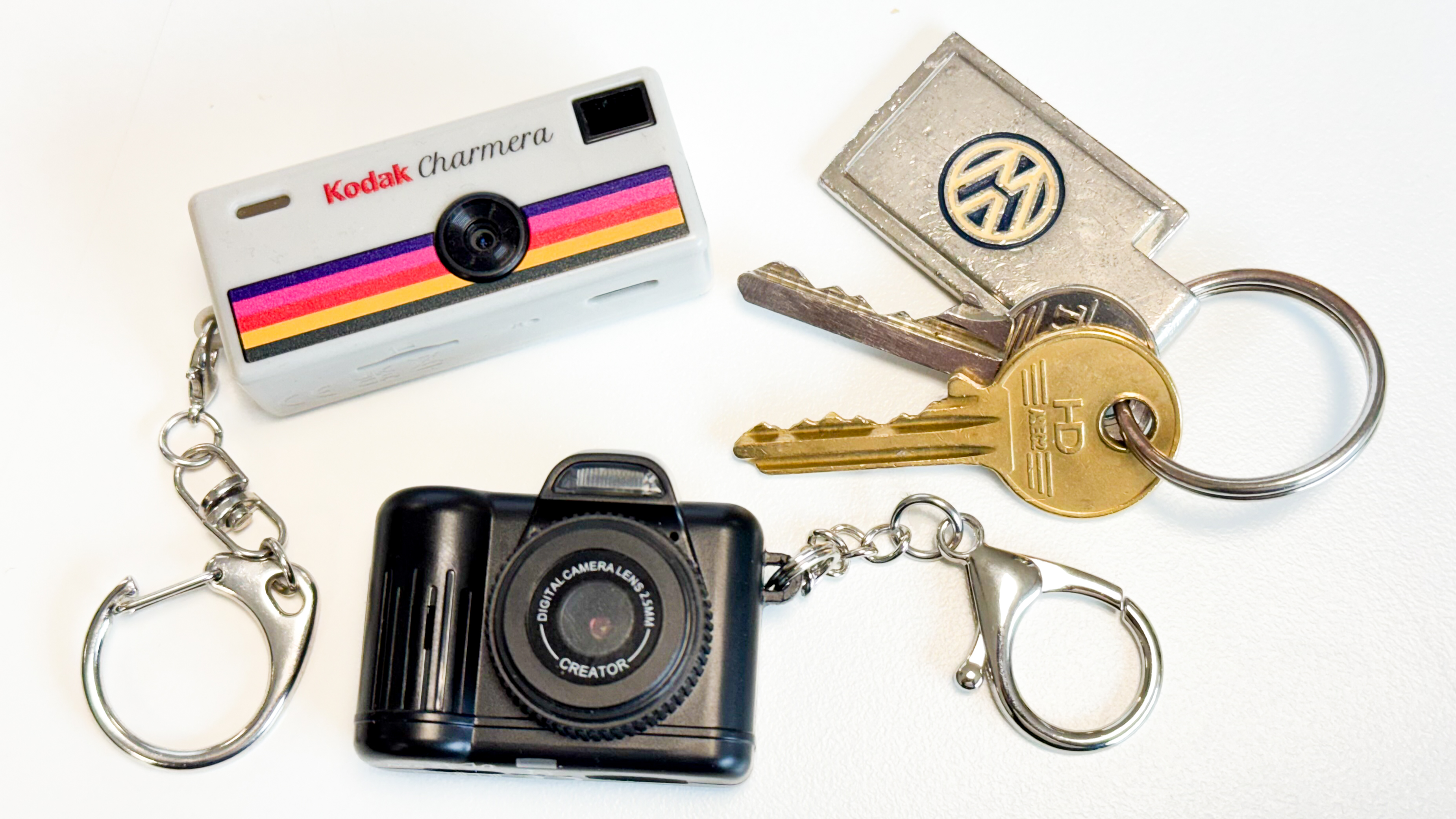 Kodak Charmera and Photo Creator Mini Cam keychain cameras with a set of keys on a plain white background