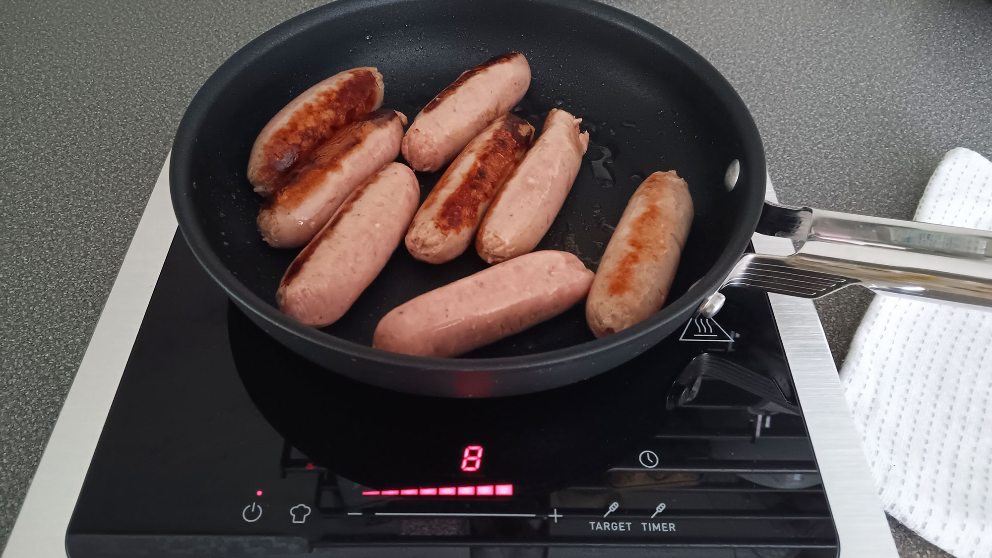 Sausages frying on Smeg Portable Induction Cooktop