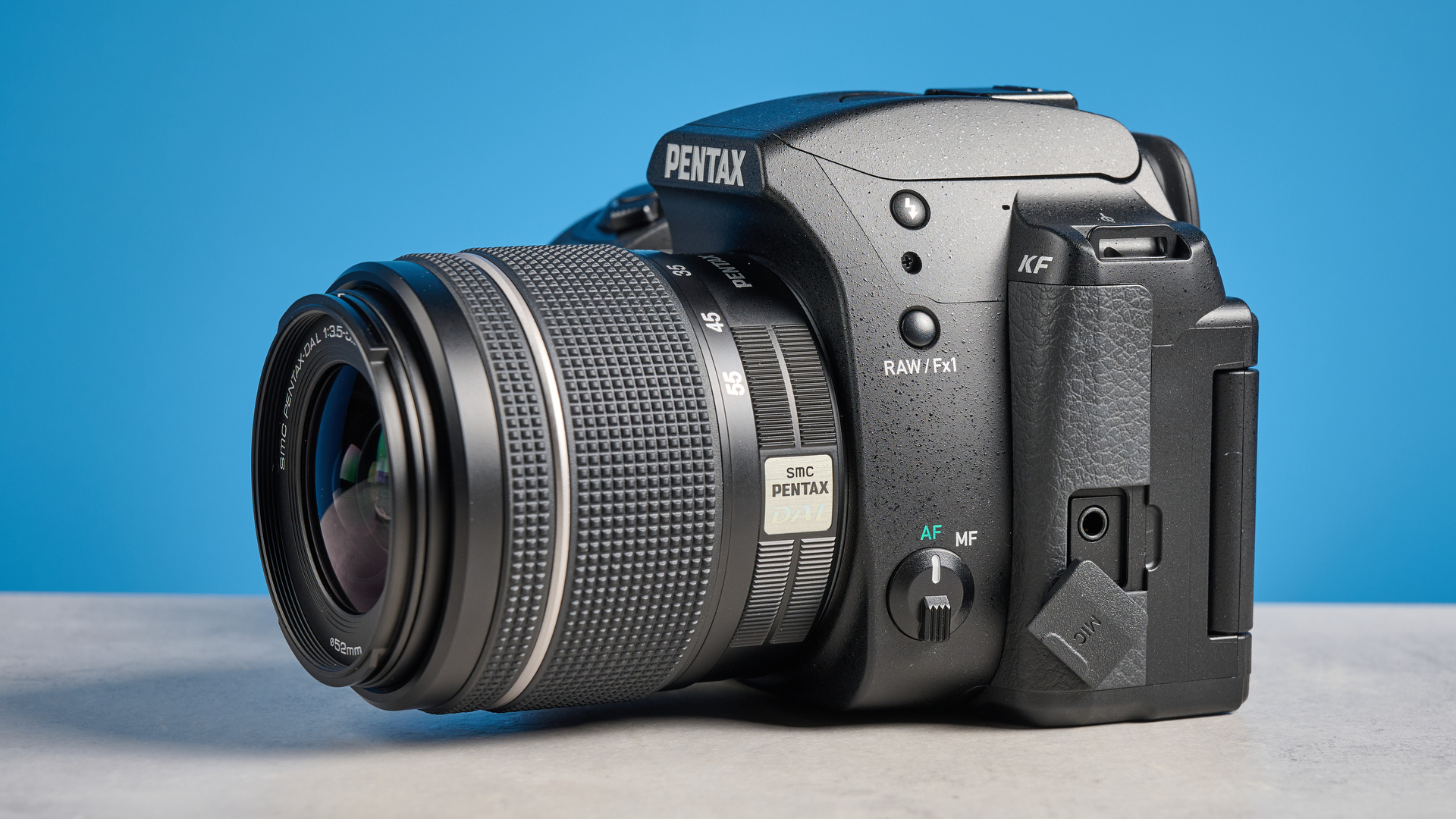 Pentax KF DSLR camera photographed on a blue background