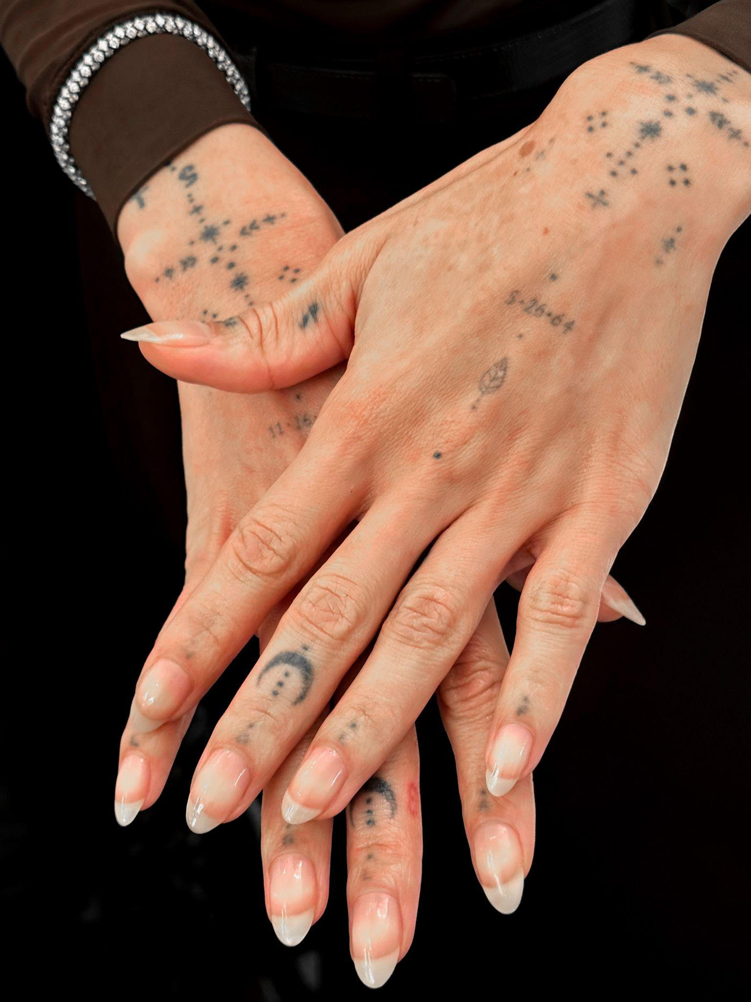 a close up photo of a person with tattooed hands wearing a plain manicure