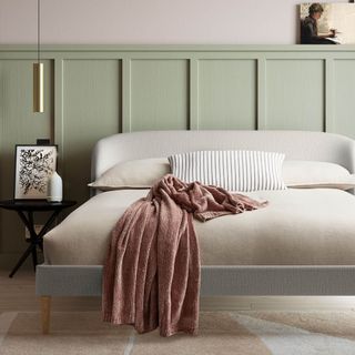 The cream upholstered Feather & Black Cambourne Bed in a green panelled bedroom