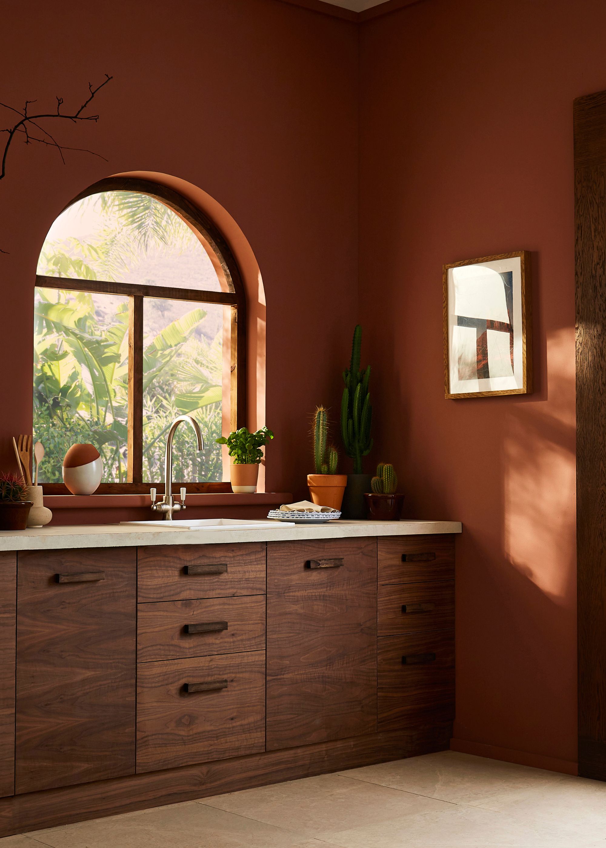 Modern kitchen with dark terracotta walls, wooden cabinets and arched window