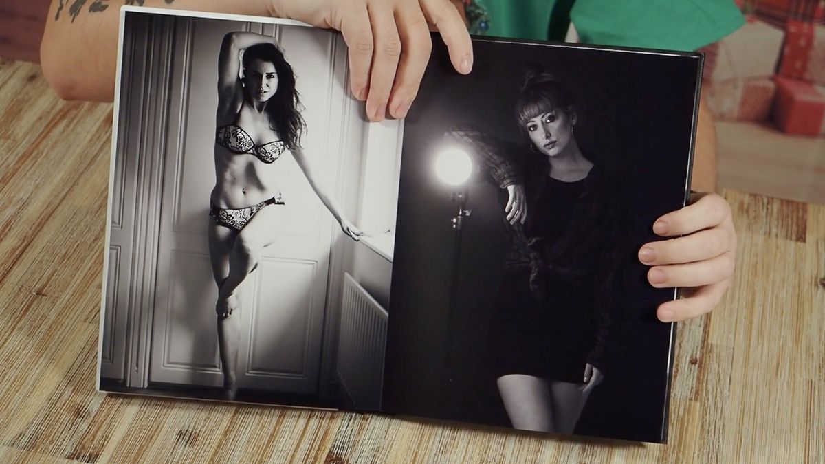 Photographer holding open a portfolio photobook, featuring female subjects