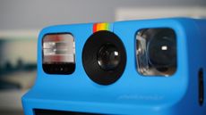 The Polaroid Go (Gen 2) on a grey background with images surrounding it