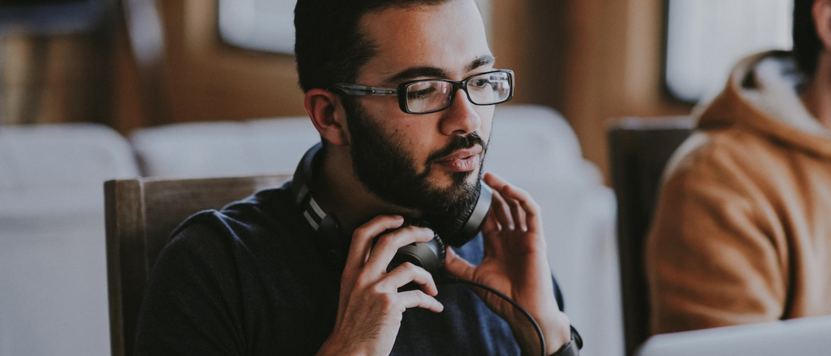 Man at computer with headphones around his neck