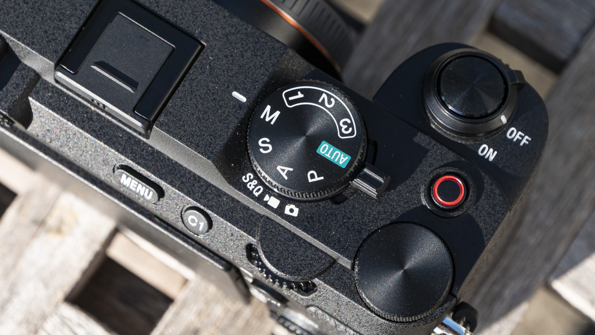 Top plate and controls of the Sony A7C R camera outside on a wooden table