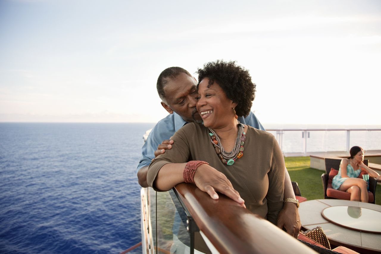 A couple smiles on the railing of a boat.