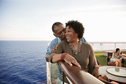 A couple smiles on the railing of a boat.