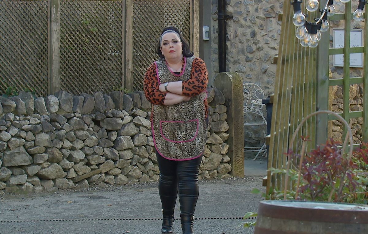 Mandy Dingle standing in the village wearing her beautician&#039;s tabard and looking worried. 