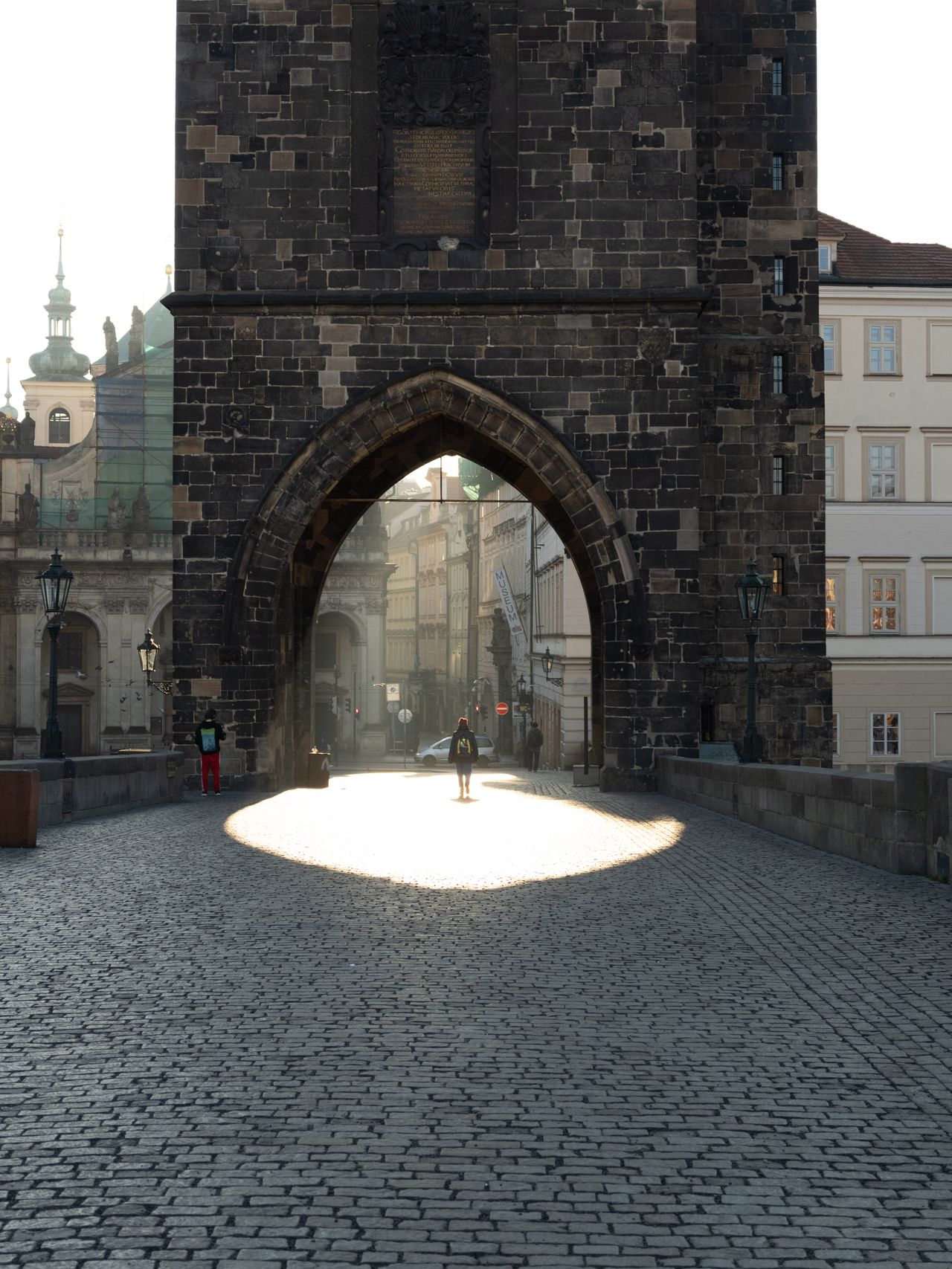 Person walking through a beam of sunlight through an archway in a stone tower