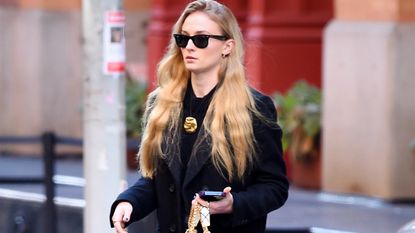 Sophie Turner in a coat, jeans, and chunky chain-link loafers