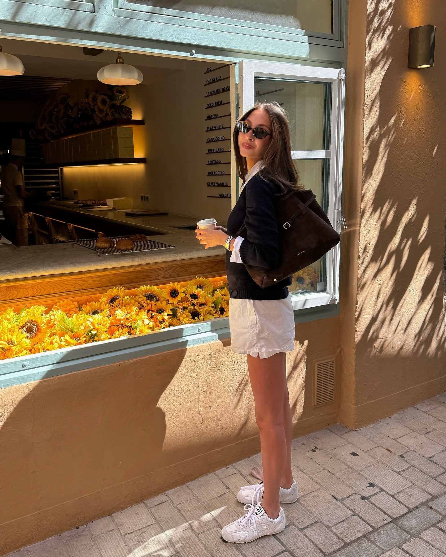Woman in white linen shorts, sweater, and white sneakers