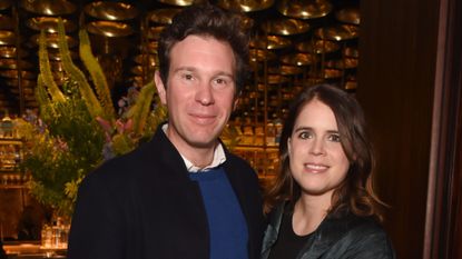 Princess Eugenie and Jack Brooksbank smiling at the camera in front of a floral display