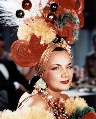 Carmen Miranda smiles while wearing a big floral headdress in That night in Rio