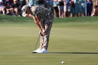 Rickie Fowler stands with his hands on his knees wearing a full camo-inspired golf uniform at the 2025 WM Phoenix Open