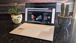 The Zenbook S 16 photographed on a dark marble surface with potted plants in the background.