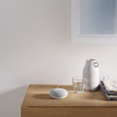 Google Nest Mini on side table next to bed