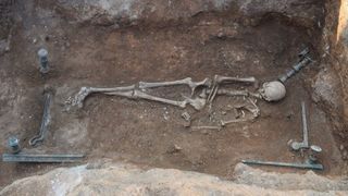 This photo shows the skeleton of a woman lying on a bronze bed.