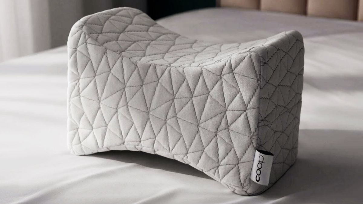 The Coop Adjustable Knee Pillow on a bed