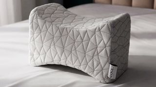 The Coop Adjustable Knee Pillow on a bed